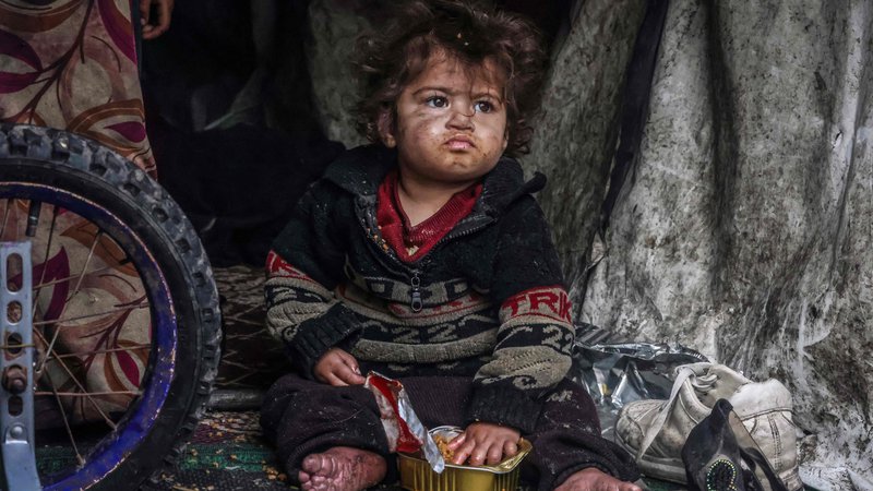 Fotografija: Palestinski otrok je hrano iz konzerve v provizoričnem šotoru v taborišču ob ulici v Rafi. Konflikt med Izraelom in Hamasom, ki divja že od 7. oktobra, je povzročil množične smrti civilistov, obsežna območja so se spremenila v opustošena območja in sprožil opozorila o grozeči lakoti na palestinskem ozemlju z 2,4 milijona prebivalcev. Foto: Mohammed Abed/Afp