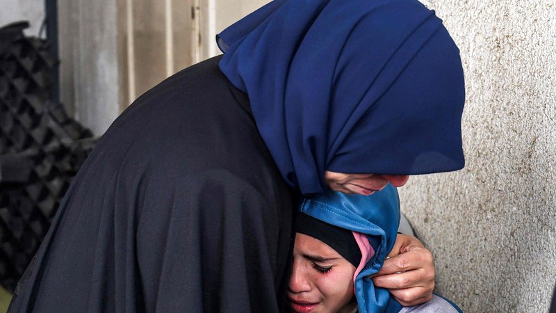 Fotografija: Ženska tolaži jokajočega otroka. FOTO: Mohammed Abed/Afp
