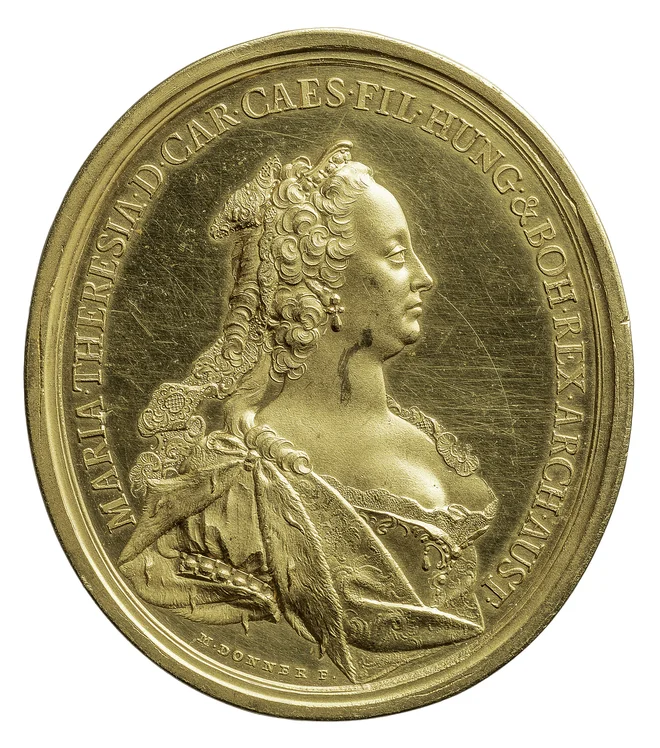 Tako imenovana Milostna medalja (Gnadenmedaille) Marije Terezije, delo Matthiasa Dönnerja, je bila izdelana iz zlata in podeljevana od leta 1743. Na hrbtni strani so simboli cesarske moči in napis Iustitia et Clementia (pravičnost in milost). Od 16. stoletja so vladarji podeljevali takšne medalje članom dinastij, pa tudi tistim ljudem, ki so bili zaslužni za dvor. Praviloma so imele podobo trenutnega vladarja in so bile večinoma ovalne oblike. Dovoljeno jih je bilo nositi na vidnem mestu in veljajo za predhodnice ordenov. FOTO: KHM Museumsverband