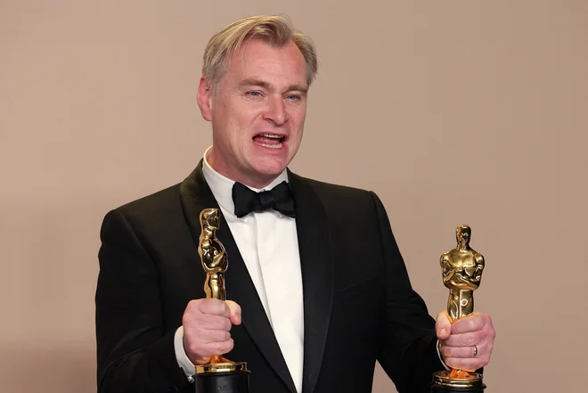 Režiser Christopher Nolan z dvema od sedmih zlatih kipcev za Oppenheimerja, ki je zdaj doživel tudi japonsko premiero. FOTO: Carlos Barria/Reuters