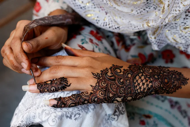 Pakistansko dekle si na roke nanaša hano pred praznovanjem konca postnega meseca ramadan v Karačiju med čakanjem na stranke. Foto: Akhtar Soomro/Reuters