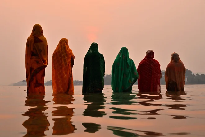 Hindujske vernice molijo bogu sonca na bregu reke Brahmaputre med festivalom »Chaiti Chhath Puja« v indijskem Guwahatiju. Foto: Biju Boro/Afp
