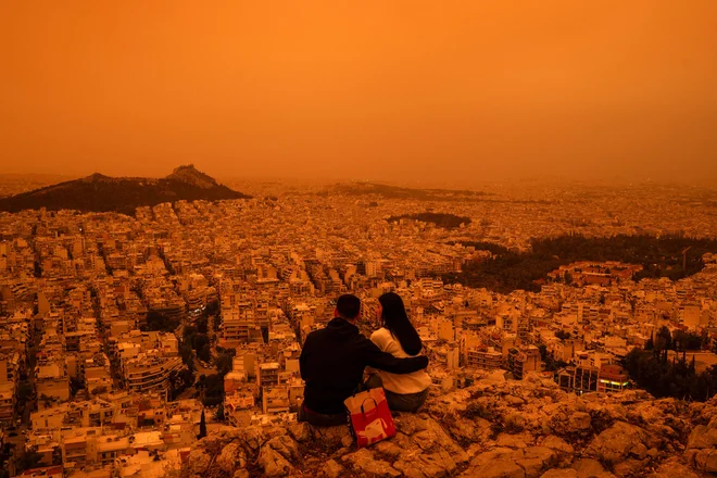 Prah, ki so ga poimenovali Minervina rdeča, je ob torkovem mraku grško prestolnico prekril z marsovskim filtrom. FOTO: Angelos Tzortzinis/AFP