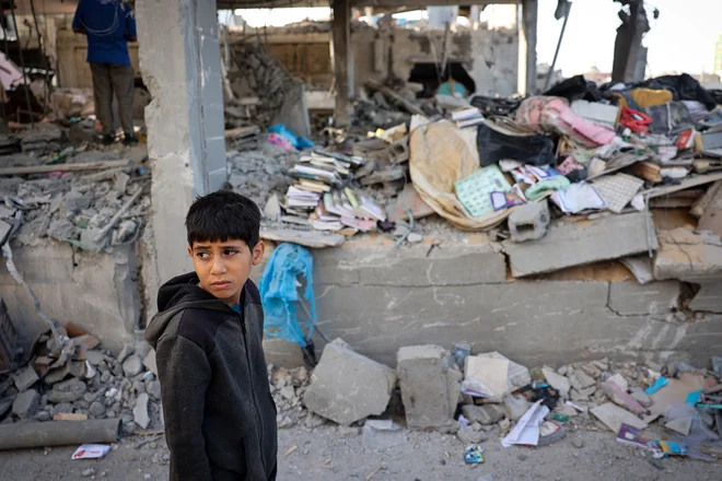 Palestinski deček ob ruševinah, ki so jih povzročili izraelski napadi. FOTO: Afp