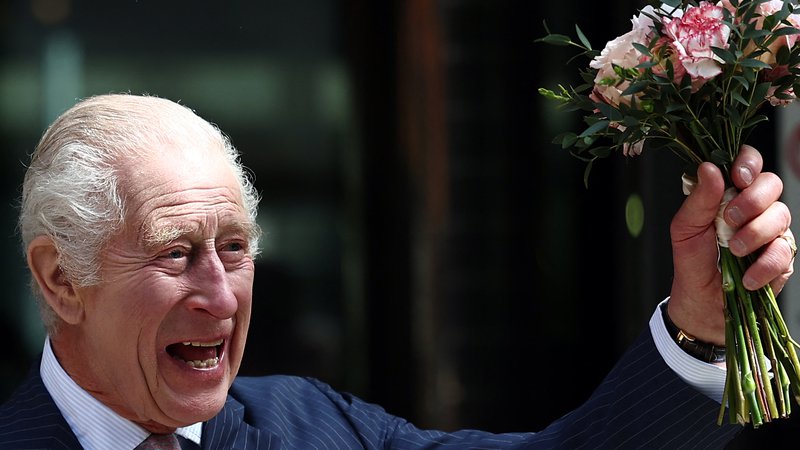 Fotografija: Kralj Karel III., ki so ga okronali pred natanko letom dni, se še vedno zdravi za rakom. Tako je pomahal s cvetjem oboževalcem pred centrom za zdravljenje raka Macmillan v Londonu, ki ga je po daljši odsotnosti iz javnosti izbral za svoj prvi obisk. FOTO: Henry Nicholls/AFP