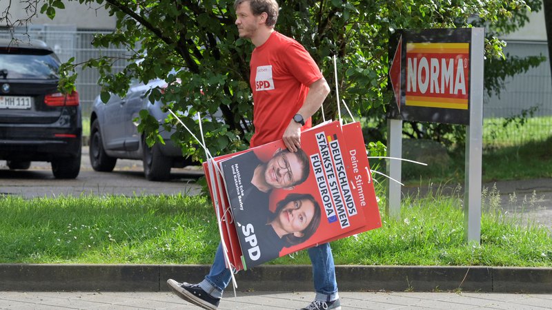 Fotografija: Prostovoljec s plakatom Matthiasa Eckeja FOTO: Matthias Rietschel/Reuters
