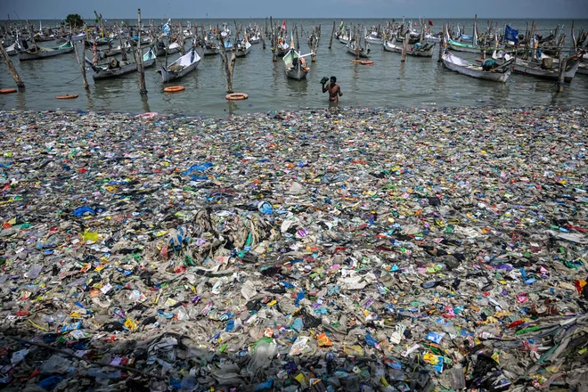 Ribič se vrača na obalo sredi morja smeti na plaži v Bangkalanu na otoku Madura v provinci na vzhodu Jave. Foto: Juni Kriswanto/Afp