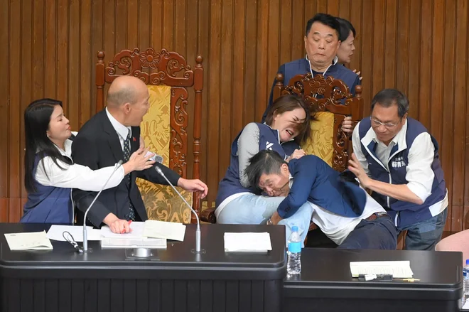 Tajvanski poslanec vladajoče Demokratične napredne stranke (DPP) Chung Chia-pin je zgrabil glavnega člana opozicijske stranke Kuomintanga (KMT) Chen Ching-huija, medtem ko predsednik parlamenta Han Kuo-yu vse skupaj opazuje med glasovanjem o zakonu o reformi parlamenta v parlamentu v Tajpeju. Foto: Sam Yeh/Afp