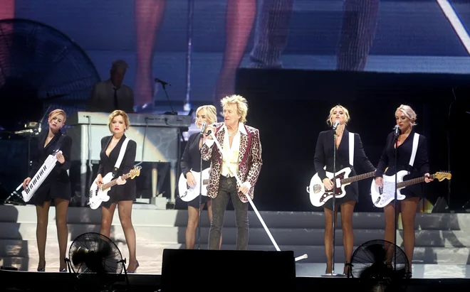 Zimzeleni Rod Stewart je ljubljanski koncert začel z uspešnico Roberta Palmerja Addicted to Love, znano po videospotu s seksapilno spremljevalno zasedbo. FOTO: Blaž Samec/Delo