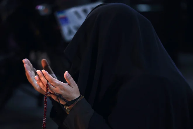 Iranka med molitvijo, še preden so izvedeli, da je iranski predsednik umrl v nesreči. FOTO: Atta Kenare/AFP