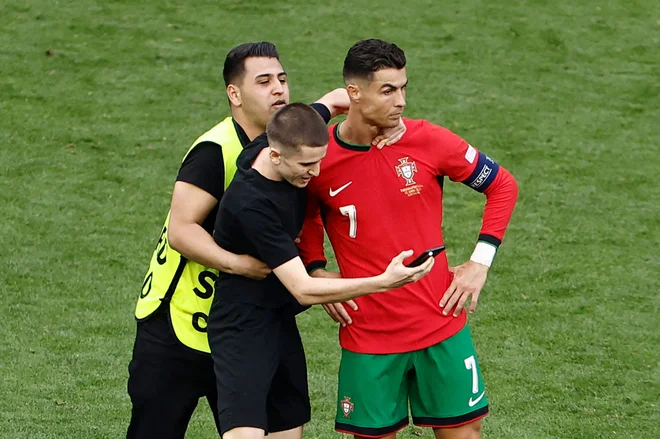Na tekmi med Portugalsko in Turčijo je na igrišče prišel nepovabljen gost in posnel selfi s Cristianom Ronaldom. FOTO: Kenzo Tribouillard/AFP