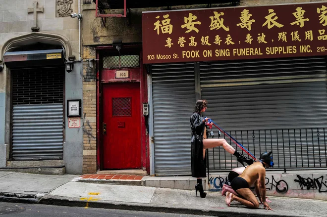 V kitajski četrti na Manhattenu ženska, oblečena kot domina, pozira fotografu z moškima, ki igrata njenega sužnja z živalsko masko. Foto: Charly Triballeau/Afp