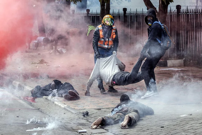 Protestniki nosijo ranjenega moškega pred kenijskim parlamentom med vsenacionalno stavko v znak protesta proti povišanju davkov in zakonu o financah v središču Nairobija, Med torkovimi protesti proti predlaganemu davčnemu zakonu je po navedbah združenja kenijskih zdravnikov v Nairobiju umrlo najmanj 13 ljudi, še več deset je ranjenih. Protestniki so prebili policijske barikade in vdrli v parlament, kjer so povzročili uničenje. Kenijski obrambni minister Aden Bare je v odziv na izgrede na ulice v pomoč policiji poslal vojsko, predsednik Ruto pa je napovedal, da oblasti ne bodo tolerirale nasilja in brezvladja. Foto: Luis Tato/Afp
