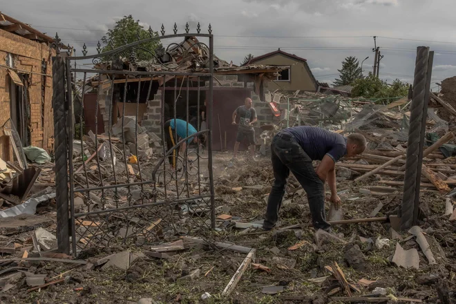 Po ruskih raketnih napadih na Pokrovsk, mesto v vzhodni Ukrajini, v katerih so izgubili življenje štirje ljudje, več deset pa je bilo ranjenih, so prebivalci takole poskušali počistiti, kar je ostalo od njihovih domov. FOTO: Roman Pilipey/AFP