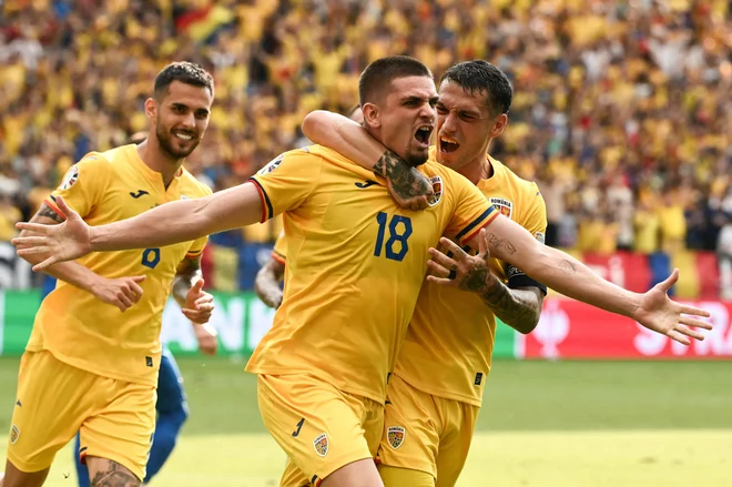 Razvan Marin (na sredini) se je takole veselil izenačujočega gola za Romunijo proti Slovaški. FOTO: Angelos Tzortzinis/AFP