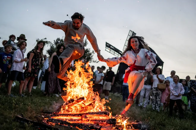 Ljudje skačejo čez ogenj v ukrajinski vasi Vytachiv med praznovanjem tradicionalnega praznika Ivana Kupala, starodavne tradicije, ki izvira iz poganskih časov in je zaznamovana z velikim nočnim praznovanjem, med katerim ljudje pojejo in plešejo ob ognju, saj verjamejo, da jih bo to očistilo grehov in jih naredilo bolj zdrave. Foto: Viacheslav Ratynskyi/Reuters