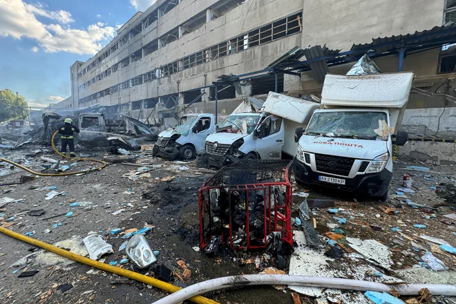 Gasilci gasijo stavbo, ki jo je po ruskem napadu zajel požar. FOTO: Vitalii Hnidyi/Reuters