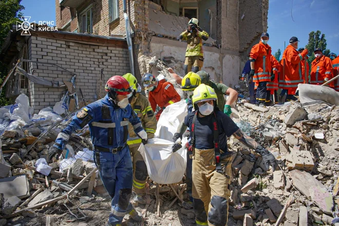 Danes so izpod ruševin v stanovanjske zgradbe v ukrajinski prestolnici potegnili truplo 21. žrtve včerajšnjih ruskih obstreljevanj z raketami dolgega dosega. FOTO: Reuters