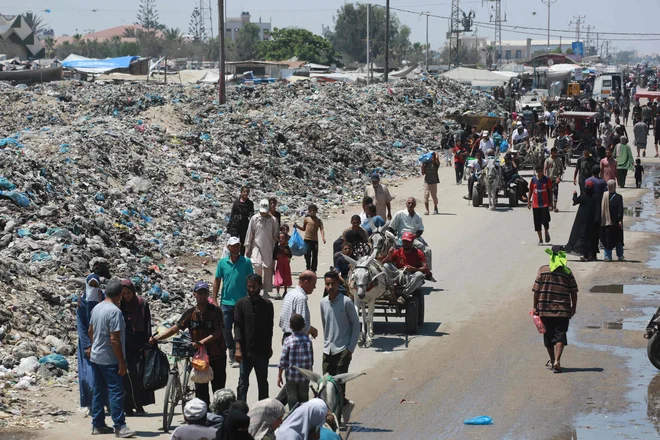 Palestinci hodijo mimo kupov smeti v Han Junisu na jugu enklave. FOTO: Bashar Taleb/AFP