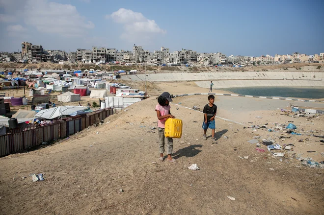 Palestinski otroci hodijo mimo zbirališča odpadne vode v Han Junisu. FOTO: Hatem Khaled/Reuters