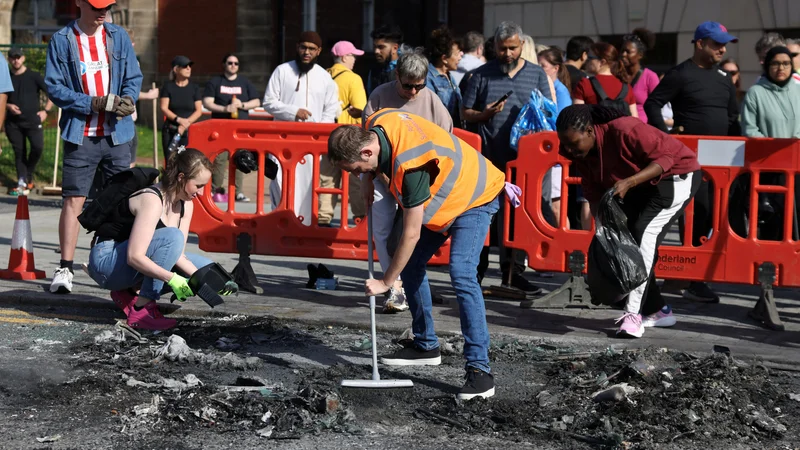 Prebivalci čistijo razbitine po izgredih. FOTO: Hollie Adams/Reuters