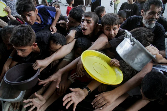 Sestradani Palestinci čakajo v vrsti za hrano. FOTO: Mahmoud Issa/Reuters