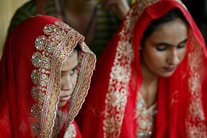 Ko so se pred dnevi nad Pakistanom začeli monsunski nalivi, sta se včeraj14-letna Shamila in njena 13-letna sestra Amina poročili v zameno za denar. To sta njuna starša storila zato, da bi družini pomagala preživeti nevarnost poplav. V zadnjih letih se je visoka stopnja porok mladoletnic v Pakistanu zmanjševala, vendar po smrtonosnih poplavah leta 2022 delavci za pravice opozarjajo, da so takšne poroke zdaj v porastu zaradi gospodarske negotovosti, ki jo povzroča podnebje. Foto: Asif Hassan/Afp