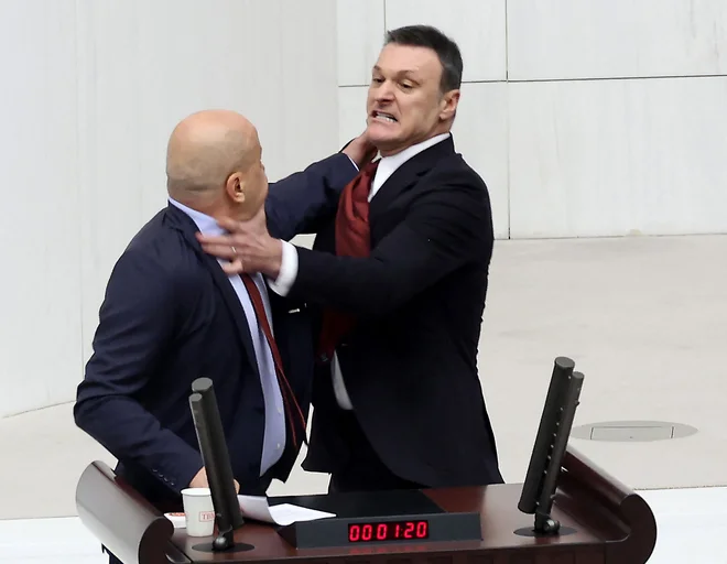 Nekdanji nogometaš in poslanec Erdoğanove stranke AKP Alpay Özalan je stopil do govorniškega odra in Ahmeta Şika porinil na tla. FOTO: Adem Altan/AFP