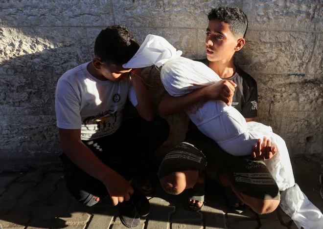 Bratranec palestinskega otroka, ki je bil ubit v izraelskem napadu, drži truplo v mestu Deir Al-Balah v osrednjem delu Gaze. Izraelska vojska je v današnjih jutranjih napadih na Gazo ubila najmanj 37 ljudi. Večino žrtev so terjali napadi na mesto Han Junis na jugu enklave. Izrael je pred tem v petek zvečer odredil nove prisilne evakuacije civilistov. Foto: Ramadan Abed/Reuters