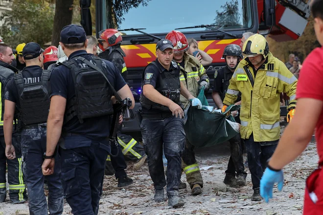 Policist in reševalci nosijo ranjenca iz stanovanjske stavbe v Lvovu, ki jo je zadel ruski napad. FOTO: Roman Baluk/Reuters