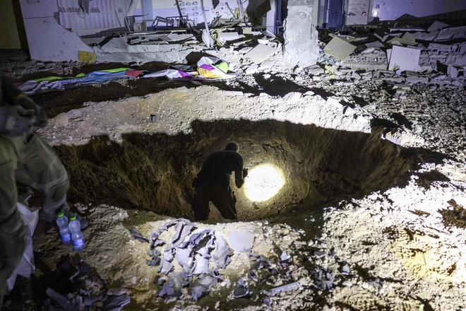 Izraelski reševalci in policisti ocenjujejo razmere po iranskem napadu. Raketa je zadela območje šole v mestu Gedera na jugu Izraela. FOTO: Menahem Kahana/AFP