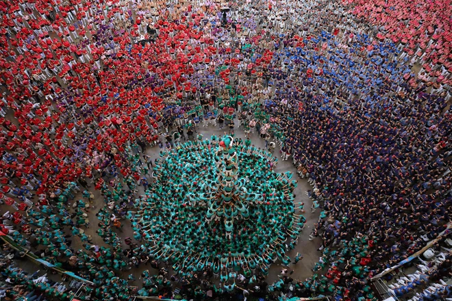Člani ekipe Castellers de Vilafranca oblikujejo »castell« (človeški stolp) med 26. tekmovanjem Castells v španski Tarragoni. Na tekmovanju človeških stolpov sodeluje več ekip, ki poskušajo zgraditi čim višjo konstrukcijo človeškega stolpa. Foto: Lluis Gene/Afp