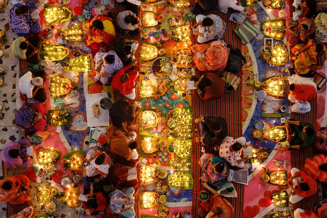 Hindujski verniki sedijo med oljnimi svetilkami in svečami v templju v Daki ter molijo k hindujskemu svetniku in filozofu med praznovanjem festivala Rakher Upobash. Foto: Mohammad Ponir Hossain/Reuters