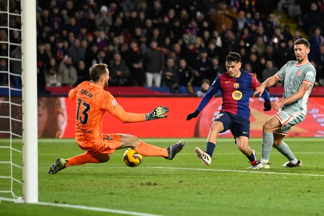 Jan Oblak pogoste rešuje soigralce. Ta fotografija razkriva njegovo obrambo proti nevarnem Pedriju na tekmi v Barceloni. FOTO: Josep Lago/AFP