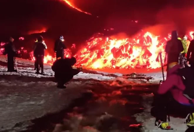 Nad čudom narave očarani obiskovalci vulkana Etna tik ob vrelem potoku, ki je nastal po eksploziji. FOTO: posnetek zaslona/facebook
