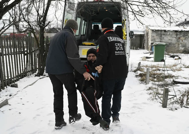 Moška evakuirata 73-letnega Volodimirja v vozilo dobrodelne fundacije East SOS iz njegove hiše v vasi Černigivka blizu frontnega mesta Pokrovsk v regiji Doneck. Foto: Genya Savilov/Afp