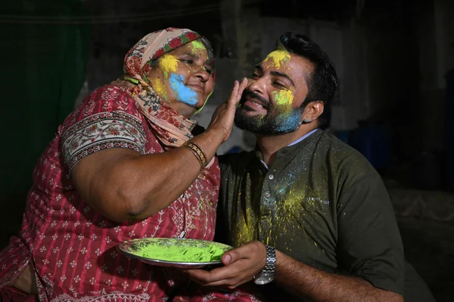 Mati barva obraz svojega sina ob praznovanju hindujskega praznika Holi v puščavskem mestu Mithi na jugovzhodu Pakistana. V pakistansikem puščavskem mestu hindujci pripravljajo obroke za muslimane, ki se postijo, ti pa se zberejo, da bi pozdravili procesijo ob prazniku Holi, kar je redek trenutek verske solidarnosti v tej islamski državi. Foto: Asif Hassan/Afp