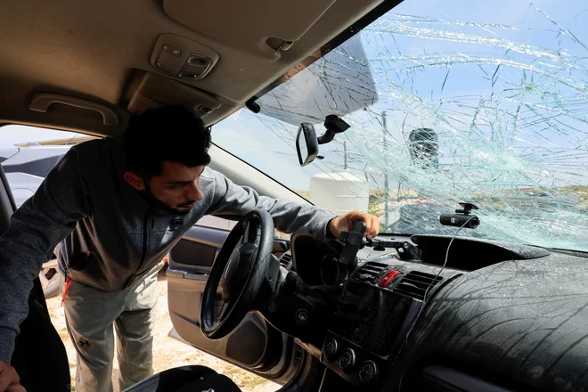 Sorežiser in eden od protagonistov Edine zemlje Basil Adra je preveril škodo na avtomobilu. Foto Mussa Issa Qawasma/Reuters