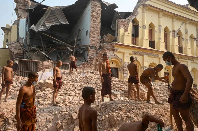 Budistični menihi stojijo na ruševinah in čistijo ostanke v poškodovanem samostanu Thahtay Kyaung v Mandalaju, pet dni po močnem potresu v Burmi. Foto: Sai Aung Main/Afp