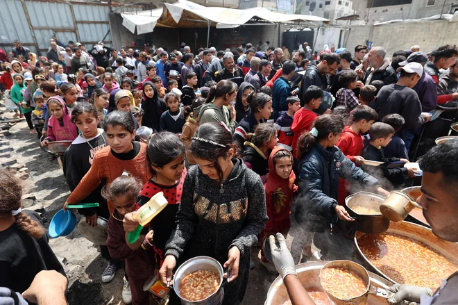 Palestinci čakajo na lokaciji za brezplačno razdeljevanje hrane, da bi prejeli svoj topli obrok v begunskem taborišču Nuseirat v osrednjem delu Gaze. Več sto tisoč ljudi v mestu Gaza je v zadnjem tednu izgubilo glavni vir čiste vode, potem ko je izraelska vojska na začetku meseca prekinila dobavo vode od izraelskega vodovodnega podjetja Mekorot, s čimer je ustavila 70 odstotkov d dobave vode. Foto: Eyad Baba/Afp