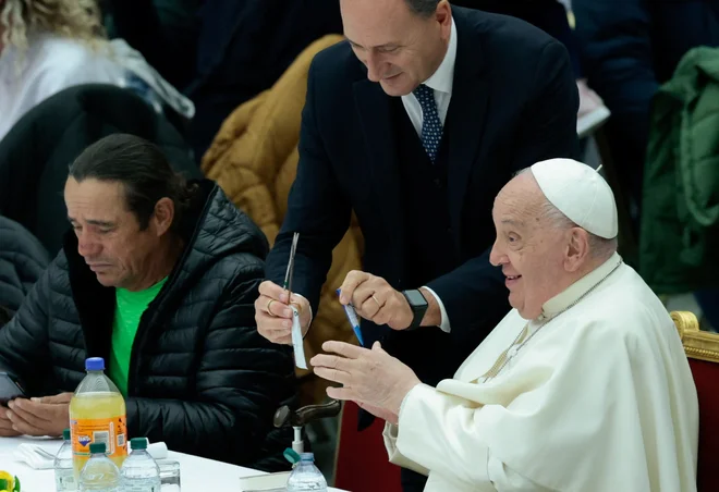 Massimiliano Strappetti pomaga papežu Frančišku, ko sodeluje pri kosilu, ki ga je Vatikan ponudil revnim ljudem na svetovni dan revnih 17. novembra lani. FOTO: Remo Casilli/Reuters