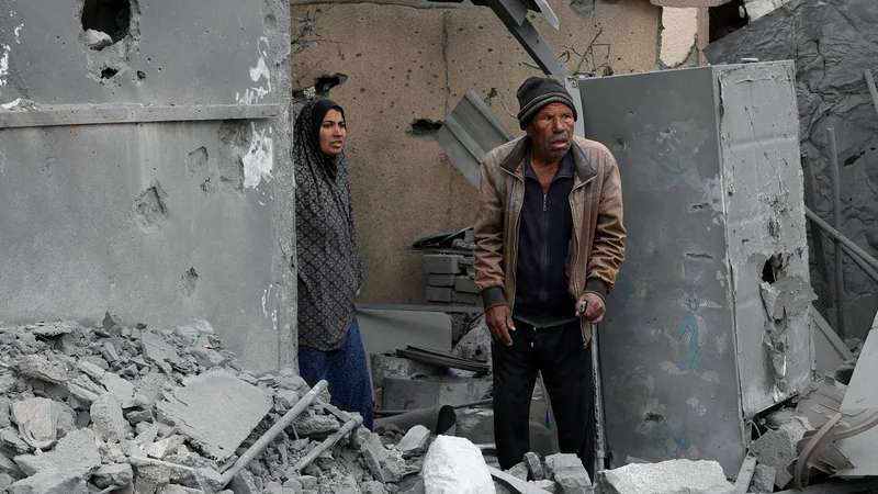 Palestinka in Palestinec pregledujeta hiše v Gazi po izraelskem zračnem napadu. FOTO: Hatem Kaled/Reuters
