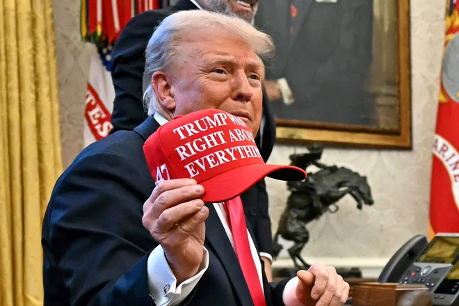 Donald Trump drži v rokah čepico z napisom Trump je imel v vsem prav. FOTO: Jim Watson/AFP