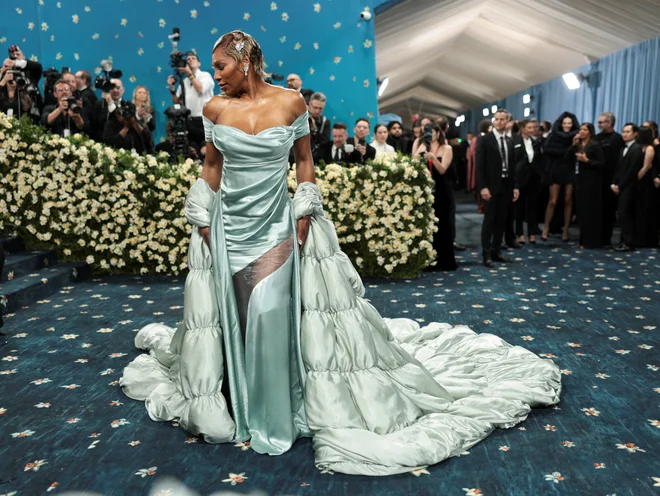 Prihod Serene Williams z nekdanjim urednikom britanskega Voguea Edwardom Enninfulom je izzval krike paparacev. Potrebovala sta dva pomočnika, da sta po stopnicah spravila njen plašč, ki ga je oblikovala blagovna znamka oblačil Moncler. FOTO: Mario Anzuoni/Reuters