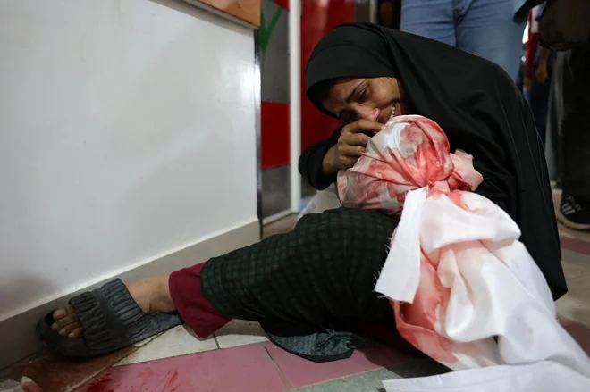 Palestinka joka, ko drži truplo njenega otroka, ubitega v izraelskih napadih na Džabalijo. Agencija za civilno zaščito Gaze je sporočila, da je bilo v izraelskih napadih na vojno opustošeno palestinsko ozemlje samo včeraj ubitih najmanj 29 ljudi, več deset pa jih je bilo ranjenih. Foto: Bashar Taleb/Afp