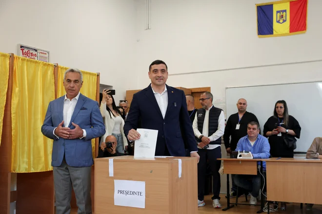 Georgescu (levo) je na volitvah pričakovano podprl skrajnodesnega kandidata Simiona (desno). FOTO: Louisa Gouliamaki/Reuters