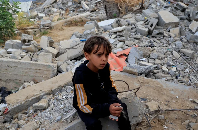 Palestinski deček na ruševinah, ki so jih povzročili izraelski izstrelki. FOTO: Hatem Khaled/Reuters
