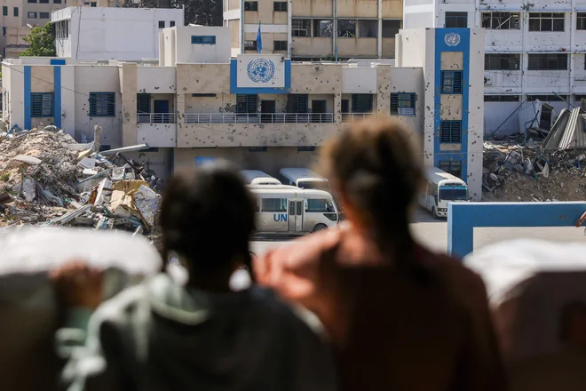 Palestinski otroci med opazovanjem zaprtega sedeža Agencije ZN za pomoč palestinskim beguncem (UNRWA) v središču Gaze. FOTO: Bashar Taleb/Afp