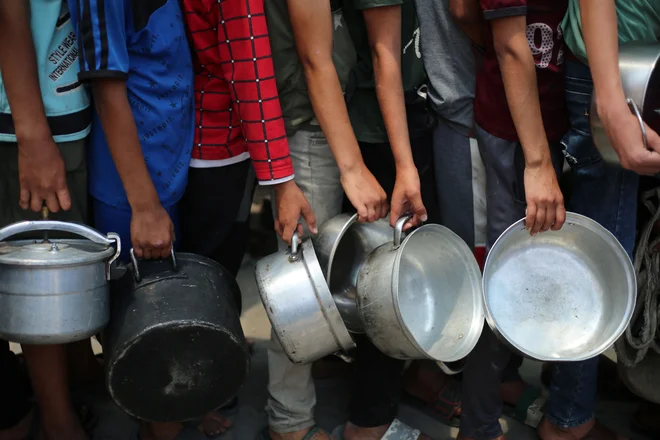 Palestinski otroci med čakanjem na hrano v Nuseiratu v osrednjem delu Gaze. FOTO: Eyad Baba/Afp