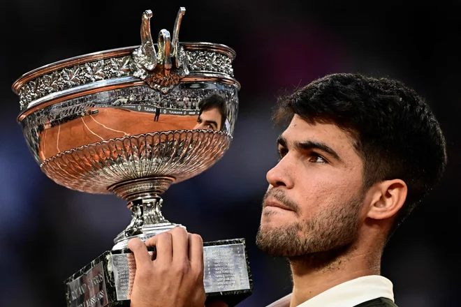 Carlos Alcaraz je takole dvignil znameniti pokal za zmagovalca turnirja v Roland Garrosu. FOTO: Julien De Rosa/AFP